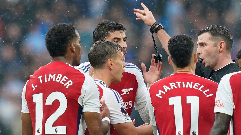 Arsenal players surround Michael Oliver